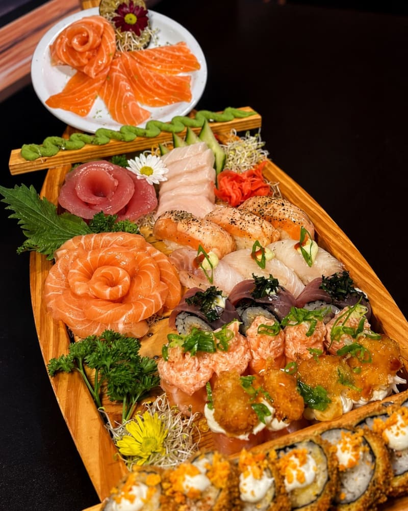 Barco de madeira com rosas de salmão, sashimis e hot rolls