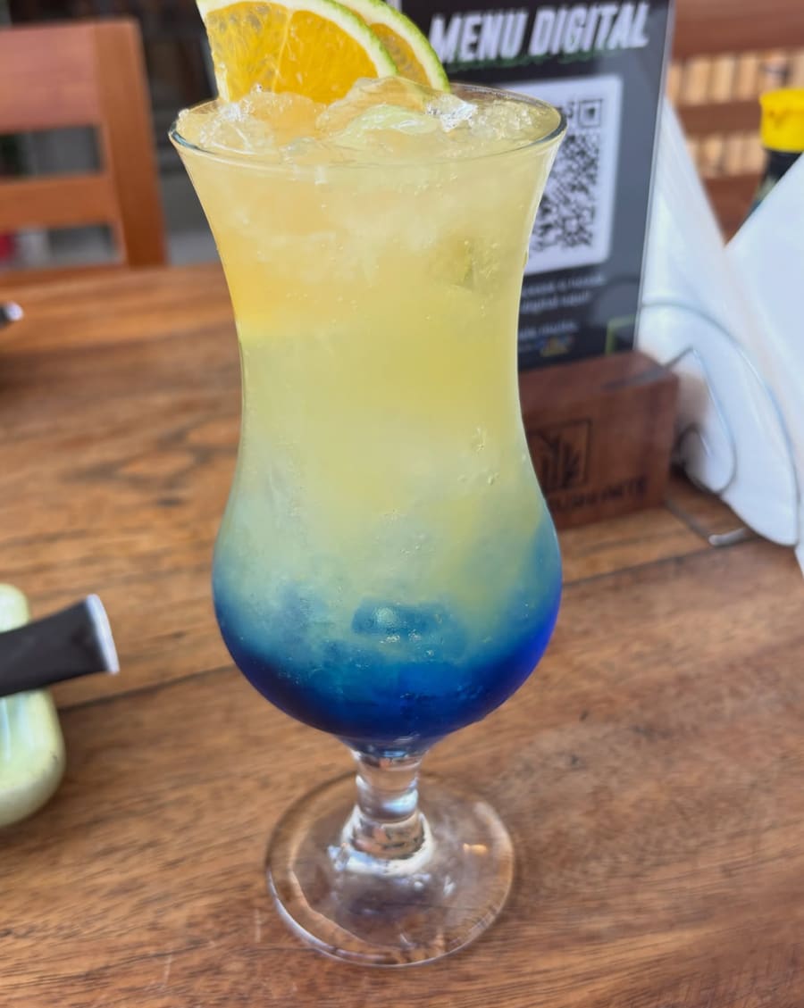 Drink em camadas azul e amarelo com rodela de laranja